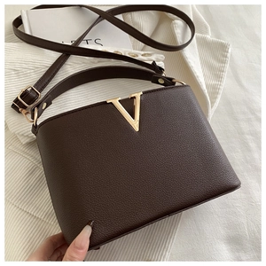Detailed view of dark brown lychee grain leather handbag with gold V-shaped metal hardware