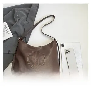Flat lay di una borsa tote in pelle marrone opaca con accessori da ufficio e lifestyle