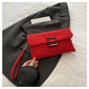 Detail of red leopard print envelope clutch bag with large black buckle and wrist strap