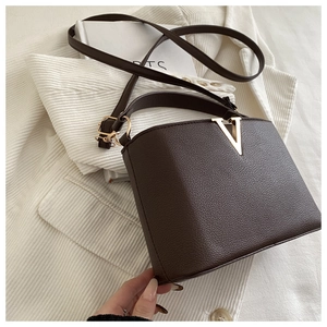 Detail of dark brown lychee grain leather handbag with gold V-shaped metal hardware