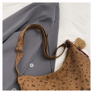 Détail du cabas en velours côtelé marron avec motifs cœurs noirs et breloque ourson