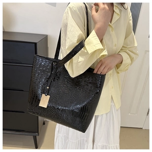 Détail du sac cabas en similicuir noir à motif crocodile avec pendentif en métal doré