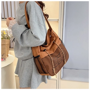 Detailed side view of brown tote bag with WSP logo and side mesh pocket on a model