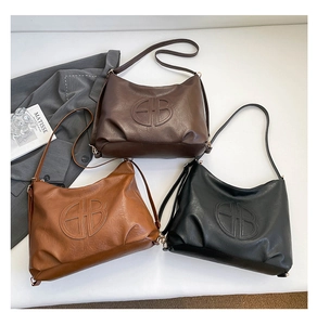 Dettaglio flat lay di borse hobo retrò in marrone scuro, caramello e nero con logo GB