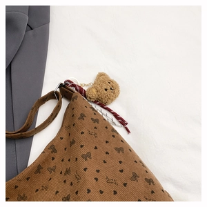 Détail du sac en velours côtelé marron avec imprimé cœur et breloque ours en peluche