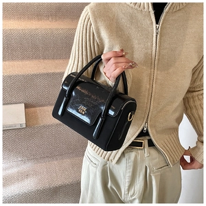 Detail of black textured handbag with golden COIH 2DN logo and mixed leather finish