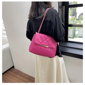 Detail of rose pink quilted chain bag with gold metal trim shown on model
