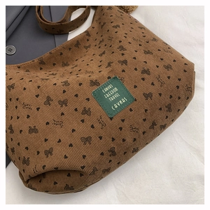 Vue détaillée du sac en velours côtelé marron avec motifs de cœurs, nœuds et étiquette