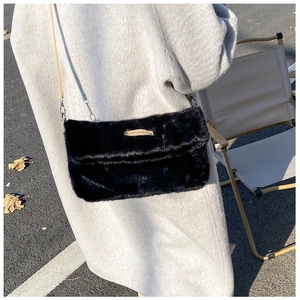 Détail d'un sac bandoulière en fausse fourrure noire porté sur un manteau d'hiver gris