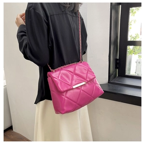 Detailed view of fuchsia quilted crossbody bag with gold chain strap worn by a model