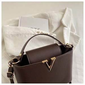 Close-up of chocolate brown leather bag with lychee texture and gold V-shaped buckle