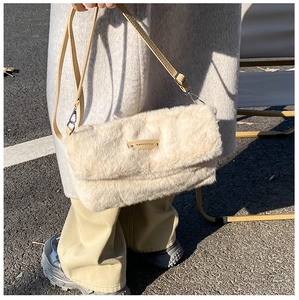 Détail du sac bandoulière en peluche crème avec étiquette logo en cuir et sangle brune