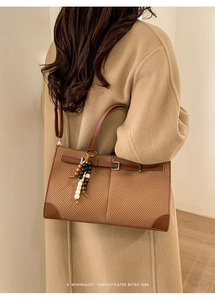 Detail of retro brown woven tote bag with wooden bead charm and smooth leather handles