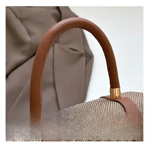 Detail of woven fabric texture and brown leather handle with golden metal accents