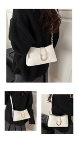 Détail du sac sous le bras en cuir blanc avec boucle fer à cheval dorée et bandoulière