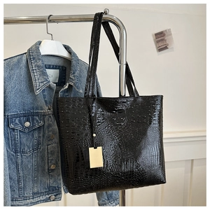 Détail d'un sac cabas en cuir PU noir à motif crocodile avec pendentif doré
