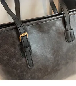 Macro shot of charcoal grey tote bag with soft leather texture and golden metal buckle detail