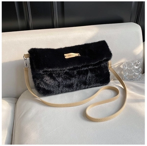 Détail d'un sac en fausse fourrure noire avec bandoulière en cuir sur un canapé blanc