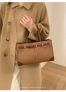 Detail of tan woven retro tote bag with brown leather trim and metallic buckle design