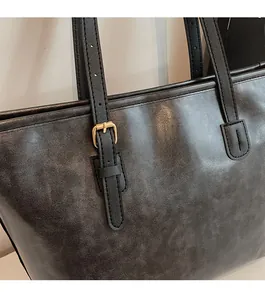 Detail of oil-wax leather texture and adjustable golden metal buckle on tote bag
