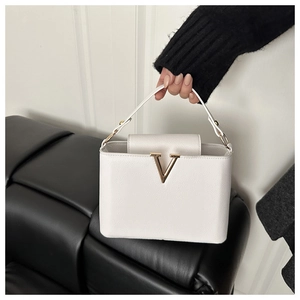 Detailed macro view of white lychee pattern leather handbag with gold V-shape buckle