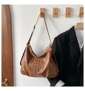 Dettaglio di una borsa hobo marrone con logo circolare a rilievo e morbida pelle