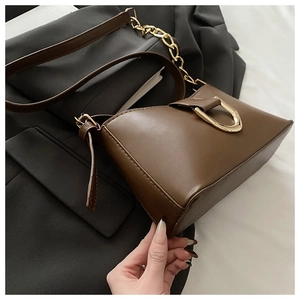 Détail d'un sac baguette en cuir marron foncé avec un fermoir à boucle en D doré chic