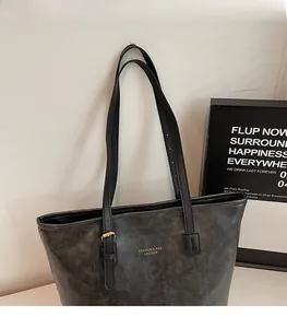Detail of grey oil wax leather tote bag featuring gold embossed text and adjustable strap