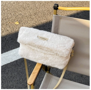 Détail du sac à bandoulière en fausse fourrure pelucheuse blanc cassé sur une chaise