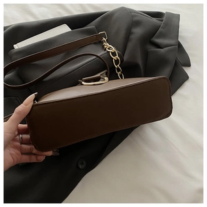 Détail du sac à bandoulière marron avec coutures précises et bandoulière chaîne dorée