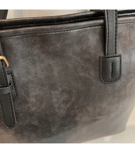 Detail of dark leather tote bag featuring gold FASHION & BAG lettering and texture