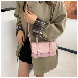 Pink crossbody bag with woven texture detail and gold hardware shown on a model