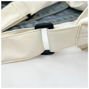 Detail of adjustable white woven strap with black plastic buckle and stitching on tote bag