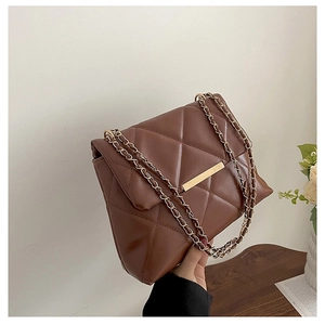 Detail of dark brown quilted crossbody bag with gold chain strap and metallic clasp