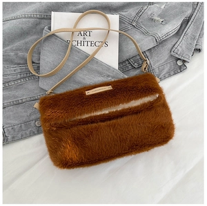 Détail d'un sac bandoulière en peluche marron avec plaque logo sur fond style de vie