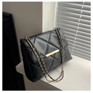 Detail of black quilted leather shoulder bag with gold chain strap and metal lock