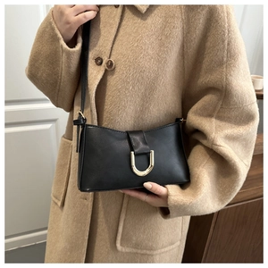 Gros plan du sac baguette en cuir noir avec une boucle dorée en U élégante et raffinée