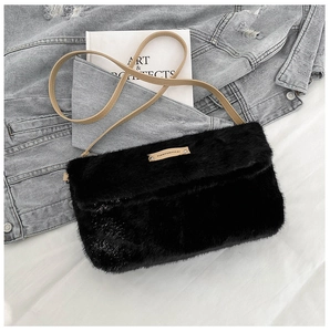 Détail d'un sac en fausse fourrure noire avec plaque dorée rivetée sur fond de jean