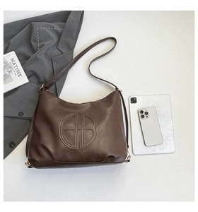 Borsa tote vintage marrone con logo a rilievo e accessori lifestyle su piano d'appoggio