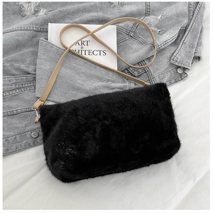Détail du sac bandoulière en fausse fourrure noire avec fine lanière marron sur denim