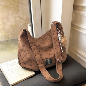 Sac hobo en velours marron avec motifs cœurs et breloque sur surface grise