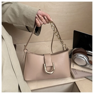 Détail du sac baguette en cuir beige avec boucle dorée et bandoulières chaîne doubles