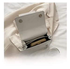 Interior capacity of the white chain bag showing a wallet and smartphone inside