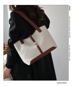 Detailed view of cream woven texture tote bag with brown leather trim and gold metal lock