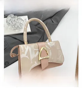Detail view of pink leather handbag with gold horseshoe buckle and top handle