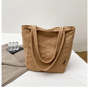 Detailed close-up of caramel corduroy tote bag texture and side decorative woven label