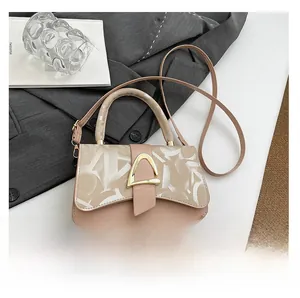 Detail of elegant beige crossbody bag with golden D-ring buckle on gray suit background