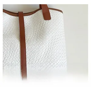 Close-up of white crocodile texture tote bag with brown leather trim and gold twist lock