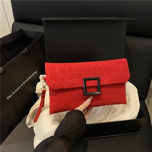 Red leopard print envelope clutch with a large black buckle and leather wrist strap