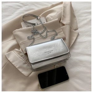 Detailed top view of silver rectangular chain bag with embossed text on textured fabric